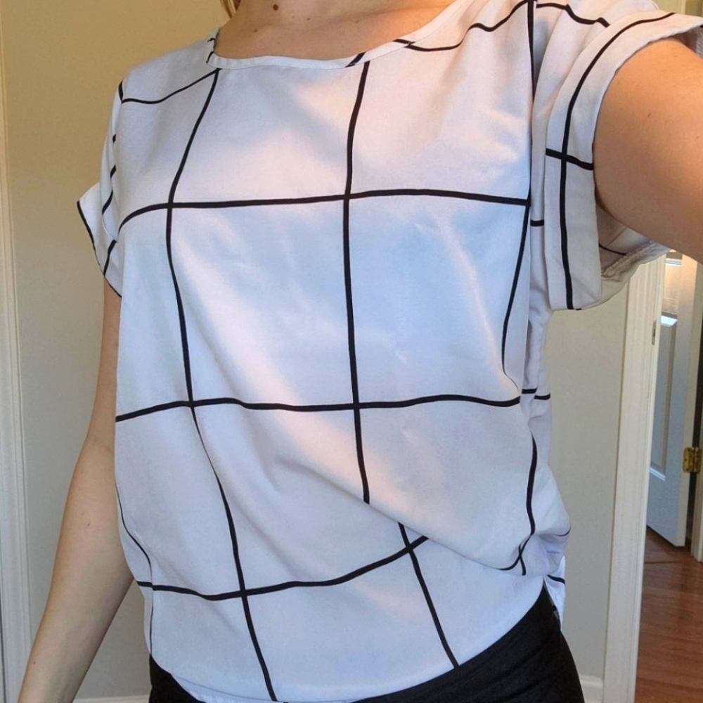 This white top features stylish black grid lines and cuffed sleeves.